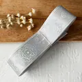 Macro shot of silver holographic ribbon roll with magical star and geometric pattern details - Plain Silver Grey Bottle 4.5 Meters Long And Approximately 2.5 Cm Wide.