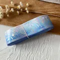 Roll of holographic blue craft ribbon featuring artistic mythological dragon patterns - Mythical Blue