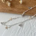 Dettaglio della catena a stelle in argento con campanellini su sfondo bianco - Stile Stella d'Argento