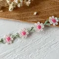 Close-up of white and pink embroidered daisy lace trim with green leaf embroidery - Pink Center White Daisy Style / Rainbow