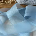 Light blue pearlescent organza ribbon for DIY crafts and gift wrapping shown on a wooden desk - Light Blue