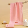 Pink cotton towel set with Goodliness embroidery shown in a warm bathroom setting - 74cmx34cm / Pink