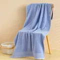 Dettaglio dell'asciugamano da bagno in cotone azzurro spesso su una sedia di legno - 140x70cm / Blu
