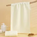 Dettaglio di asciugamani in cotone crema con bordi a costine in un ambiente spa minimale - 75x35cm / Bianco