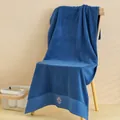 Dettaglio macro di asciugamano in cotone blu scuro con ricamo logo corona di lusso - Blu