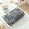 Soft dark grey cotton face towel with navy blue and white striped borders displayed on a tray - 74cmx34cm / Dark Gray