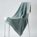 Teal blue cotton towel with geometric diamond texture hanging on a white chair - 100cm x 50cm / Malachite green