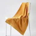 Mustard yellow cotton bath towel with geometric diamond texture on white chair - 100cm x 50cm / Wheat