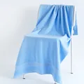 Absorbent light blue cotton bath towel with textured weave on a minimalist chair - 70x140cm / Light Blue