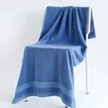 Plush blue cotton bath towel featuring honeycomb weave borders draped on a white chair - 70x140cm / Dark Blue