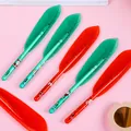 Close-up of red and green Christmas feather pens with festive Santa and reindeer patterns - Christmas Feather Style