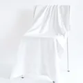 Plush white cotton bath towel featuring delicate jacquard texture draped on a chair - 70x140cm / White