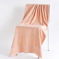 Thick peach pink cotton bath towel with textured woven stripes on a white chair - 70x140cm / Pink