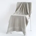 Thick light grey cotton bath towel with textured weave detail hanging on a chair - 70x140cm / Gray