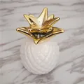 Vista superior de un adorno de piña decorativo con base blanca y corona de hojas doradas - Estilo Blanco Y Dorado / Blanco