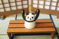 Süßer Panda-Tischaufsteller aus Harz hält Arme hoch für Karten oder Brillen auf Holzbank - Panda