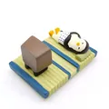 Miniatuur pinguïnfiguur op groene tatami-mat met een klein kussen en accessoires - Pinguïn Tatami