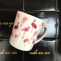 White ceramic mug featuring pink flamingo patterns placed on black gift boxes - Colorful Flamingo