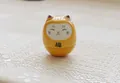 Yellow ceramic Maneki Neko Daruma doll with Fu character on light lace tablecloth - Yellow