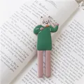 Aimant frigo chat 3D créatif avec pull vert posé sur une page de livre ouvert - Chat Style Sucette