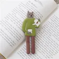 Aimant chat gris aux longues jambes en pull vert tenant une cafetière sur un livre - Chat brun avec balle