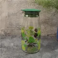 Glass water pitcher with tropical green leaf prints and a flat grass green lid - Monstera Leaf