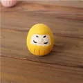 Figura japonesa de Daruma amarillo sobre madera oscura para la riqueza y prosperidad - Amarillo