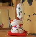 Gato de la suerte Maneki-neko japonés de cerámica blanca sobre cojín rojo - Estilo Riqueza y Fortuna