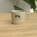 Cream ceramic coffee mug with minimalist black cat illustration and textured base - White Sesame Glazed Mug