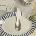 Matte stainless steel polar bear dessert spoon on a minimalist striped ceramic plate - Spoon
