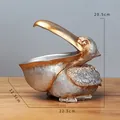 Estatua de pelícano de resina oro y plata con dimensiones para llaves y dulces - Plata Champaña