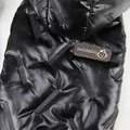 Macro shot of black glossy quilted pet jacket featuring leather brand logo patch - S / Black