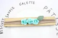Elastisches Baby-Stirnband mit drei türkisen Papierrosen und grünen Blättern - Blau