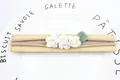 Elastisches Baby Stirnband mit drei weißen Stoffrosen und grünem Blatt auf Holz - Weiß