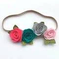 Detailed macro of handmade felt roses and green leaves on an elastic baby headband - Style 1 (Rose Red/Cyan/Gray/Pink)