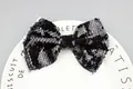 Sparkling black and silver sequined bow accessory displayed on a white decorative plate - Black