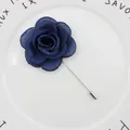 Detailed close-up of dark blue fabric rose lapel pin with textured petals on ceramic plate - Navy Blue