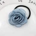 Detailansicht eines blauen Stoffrosen-Haargummis auf einem eleganten weißen Keramiktablett - Abendblau
