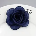 Λεπτομερής κοντινή λήψη καρφίτσας καμέλιας από μπλε ύφασμα σε λευκό κεραμικό πιάτο - Ναυτικό μπλε