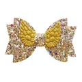 Close-up of golden glitter bow hair accessory with 3D angel wings and sequins - Gold