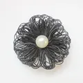 Close-up of handmade black layered silk flower brooch featuring a vintage white pearl center - Black