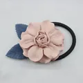 Detalle de camelia de tela rosa con hojas azules en una goma elástica negra - Rosa Claro