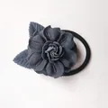 Détail d'un chouchou camélia bleu marine avec feuilles vertes sur une surface blanche - Bleu marine