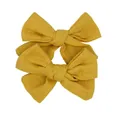 Detail of two mustard yellow linen bow hair clips with natural woven fabric texture - Turmeric