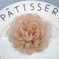 Close-up of handmade organza peony hair clip with layered petals and shimmering edges - Creamy Green