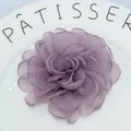 Detailed macro view of a handmade purple organza peony hair clip on a white ceramic plate - Dust Rose