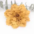 Close-up of a handmade ginger yellow satin flower with layered wavy pleated petals - Turmeric