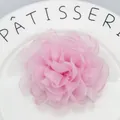 Macro shot of layered pink organza peony hair clip resting on a white ceramic plate - Pink