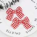 Paar rot-weiße Gingham-Schleifen aus Stoff für DIY-Mode auf weißem Keramikteller - Rot