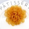 Handmade orange organza peony hair clip with multi-layered petals on a white ceramic plate - Turmeric